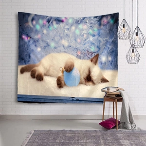 Christmas tapestry featuring a sleeping cat with blue ball hanging on a white brick wall