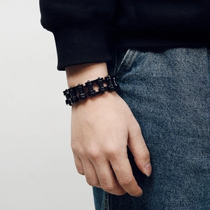 Gros plan d'un bracelet chaîne mécanique en acier inoxydable noir mat sur un mannequin