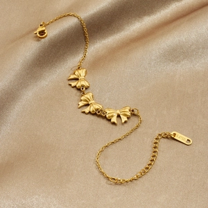 Bracelet chaîne à nœud en acier inoxydable doré sur un fond élégant en soie brillante