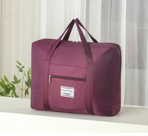 Detail of a large purple travel bag with wide handles and a front zipper pocket