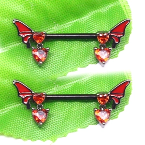 Detail of bat wings nipple rings with red heart gemstones on a green leaf