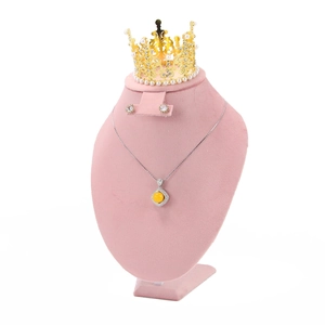 Detailed view of yellow crystal necklace and pearl crown on a pink velvet bust stand