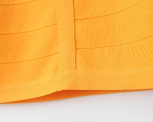 Gros plan sur le tissu tricoté orange montrant la texture dense et les coutures de qualité