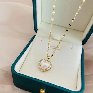 Detailed macro of gold heart pendant necklace with pearl inlay and crystals in a box