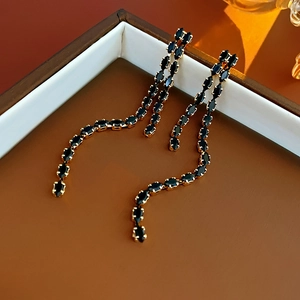 Detail of elegant gold drop fringe earrings with marquise-cut black gemstones on tray