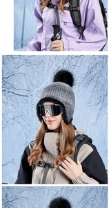 Detail view of a grey knit beanie with a thick black faux fur pompom and winter gear