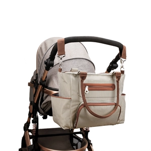 7-piece beige striped diaper bag set hanging on stroller with brown leather trim straps