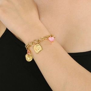 Detail of 18k gold plated chain bracelet with heart and crystal pendants on model wrist