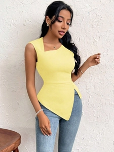 Detail of yellow slim-fit asymmetric hem top paired with blue skinny denim jeans