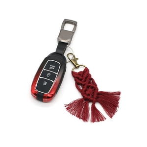 Detail of red handmade braided cotton tassel keychain with bicolor car key case and metal clasp
