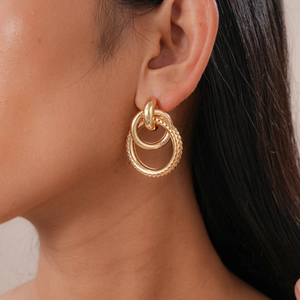 Close-up of gold interlocking hoop earrings featuring smooth and textured ring details