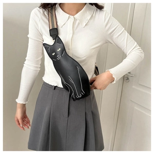 Crossbody bag in cat shape with striped strap worn by model over a white top