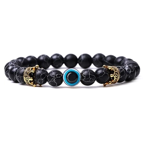 Close-up of black matte beads and blue evil eye charm with golden crown spacers