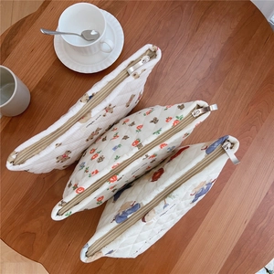Three-piece quilted cotton cosmetic bag set with bear and floral prints on wooden surface