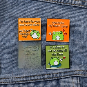 Set of 4 cute cartoon frog enamel pins with motivational quotes on denim jacket