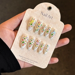 Almond-shaped press-on nails with colorful polka dots and 3D floral accents on card