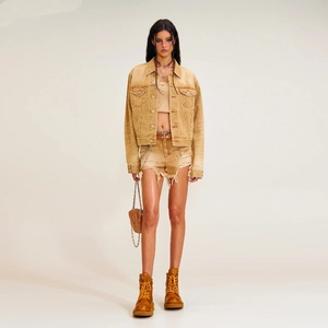 Detailed close-up of distressed denim jacket with vintage washed finish and fringe shorts