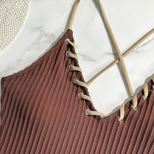 Detail of brown ribbed swimwear fabric with beige straps through silver metal eyelets