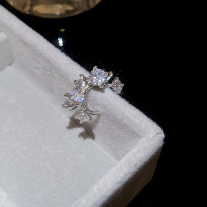 Détail macro du耳骨夹 double cœur argenté avec zircons sur boîte en velours blanc