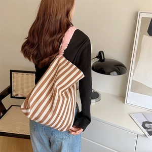 Detail of pink ruffled shoulder strap on a brown and white striped canvas tote bag