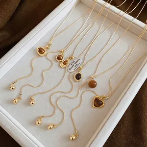 Gold necklaces set with tiger eye heart pendants on a white jewelry tray