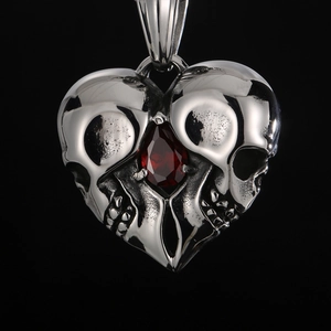 Macro view of heart-shaped twin skulls pendant with a red teardrop gemstone