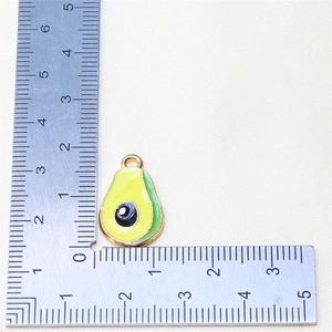 Detail showing mini avocado alloy pendant size with ruler measurement on fabric