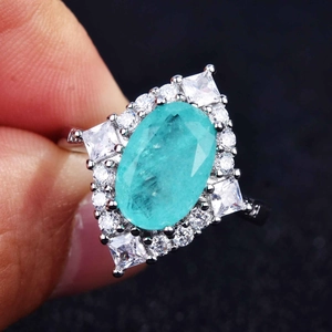 Macro shot of oval Paraiba blue gemstone ring with cluster zircon setting and silver band