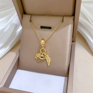 Detail of gold evil eye and feather pendant necklace inside a luxury jewelry gift box