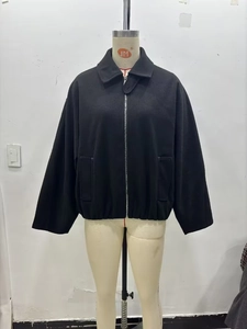Detail of black zip-up jacket featuring wide collar and elasticated waist hem for sleek fit