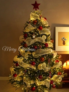 Detailed close-up of a festive Christmas tree with gold mesh ribbons and warm LED lights
