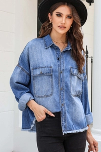 Detail shot of washed denim shirt featuring fringe hem and vintage metallic buttons