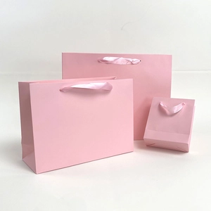 Three pink paper gift bags in small, medium, and large sizes with satin ribbon handles