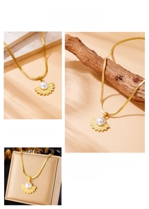Macro view of gold-plated fan-shaped feather pendant with white pearl inlay detail