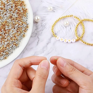 DIY jewelry making process with gold beads and white LUCKY letter beads on marble surface