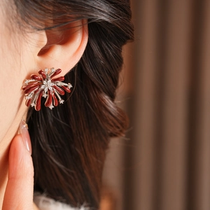 Détail de boucles d'oreilles fleurs de feu d'artifice rouges portées par un mannequin