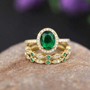 Macro shot of three-piece gold-plated ring set with oval green emerald and vintage stones
