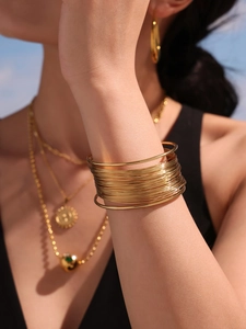Close-up of layered gold stainless steel bracelets on model arm with minimalist luxury style