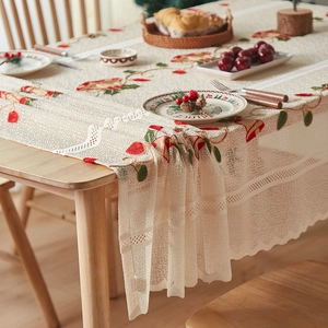 Detail of beige lace tablecloth with Christmas bell embroidery and festive holly patterns