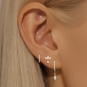 Macro shot of gold silver earrings set featuring sparkling marquise diamonds and floral stud