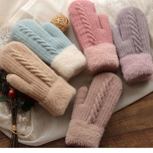 Flat lay of warm cable knit mittens with plush faux fur cuffs in assorted soft pastel colors