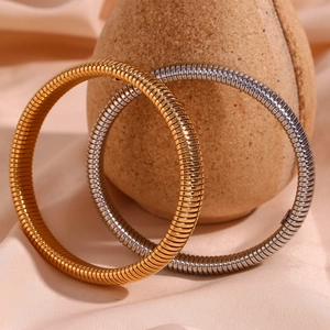 Détail des bracelets chaîne serpent de 10mm en or et argent sur un tissu élégant