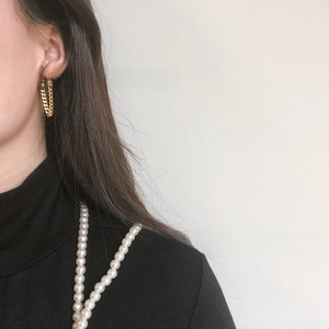 Detail of gold-plated titanium steel cuban chain tassel earrings on a model profile