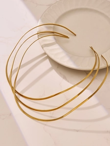 Vue rapprochée de colliers torque minimalistes en acier inoxydable doré sur marbre