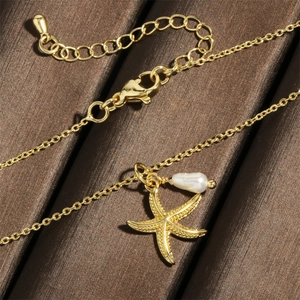 Detail of 18K gold plated starfish necklace featuring a baroque pearl and lobster clasp