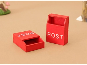 Macro view of two miniature red wooden dollhouse mailboxes with white POST lettering