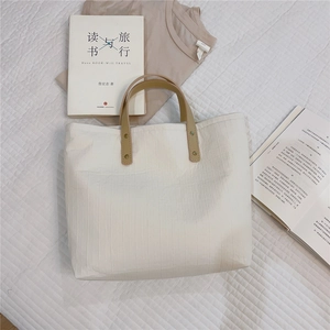 Detailed texture of beige cotton tote bag with premium brown leather handle and gold studs