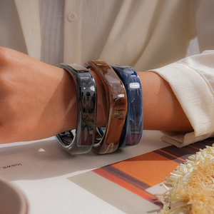 Close-up view of three marbled resin square bangles worn on a wrist
