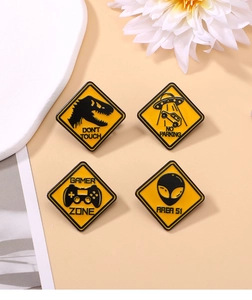 Detail of yellow enamel lapel pins with dinosaur, UFO, and gaming controller designs