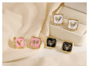 Dettaglio ravvicinato di orecchini a cuore quadrati in rosa, nero e bianco su un supporto